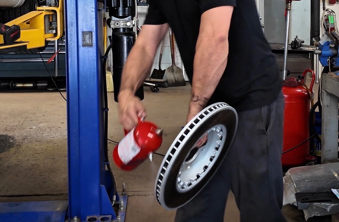 Premiere technician holding a Bentley brake caliper and rotor in the Plainfield service bay